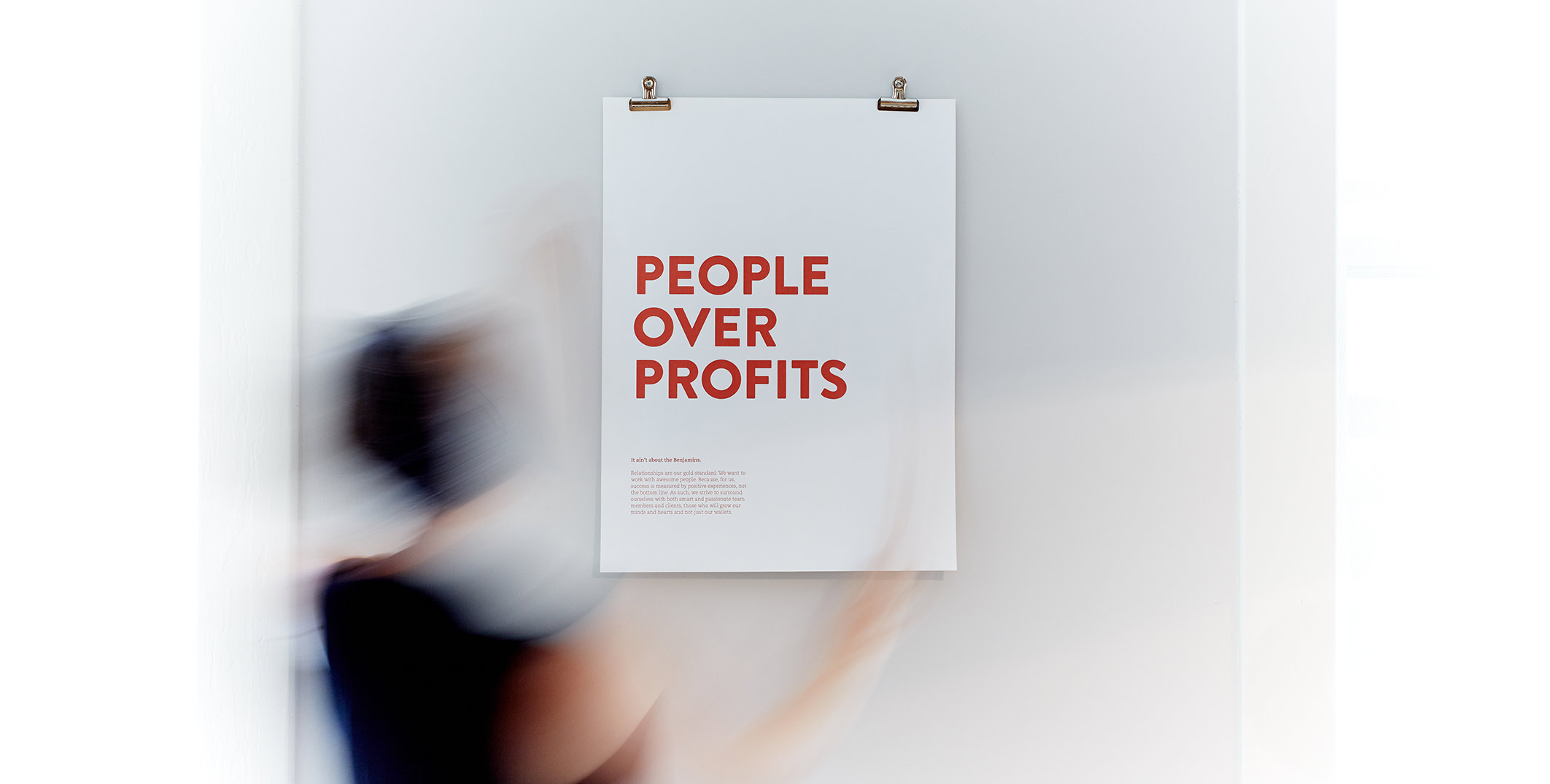 Photo of the People over Profits poster being hung on a wall.